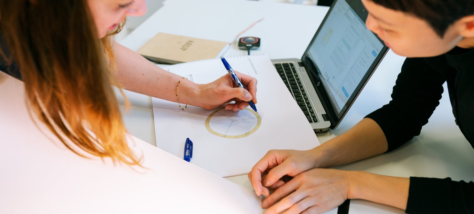 Forschung und Entwicklung Eine Frau und ein Mann beugen sich über ein Dokument und arbeiten gemeinsam daran.